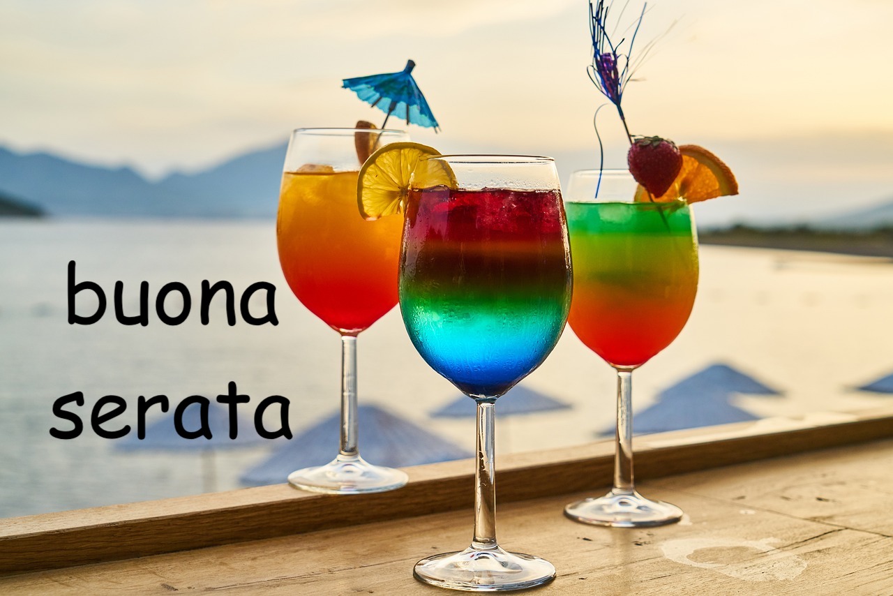 tre bicchieri con un cocktail colorato in un locale in spiaggia d'estate la sera